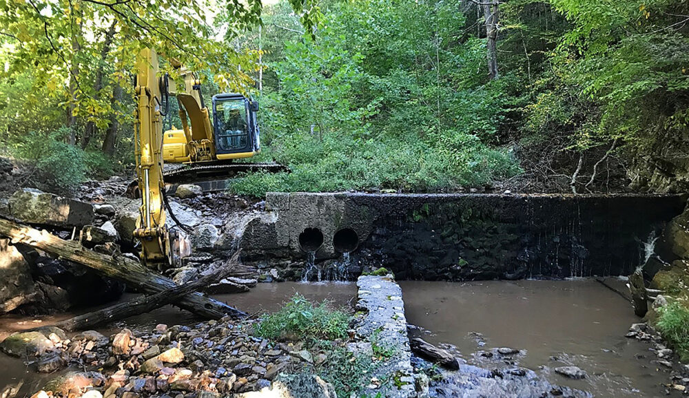 An image of the demolishment of a portion of a Dam which was funded by the DWR and trout unlimited; a portion was selected to remain for historical value but the channel was opened for greater water passage