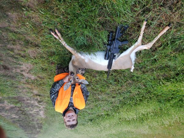 An image of a boy and the deer he has killed