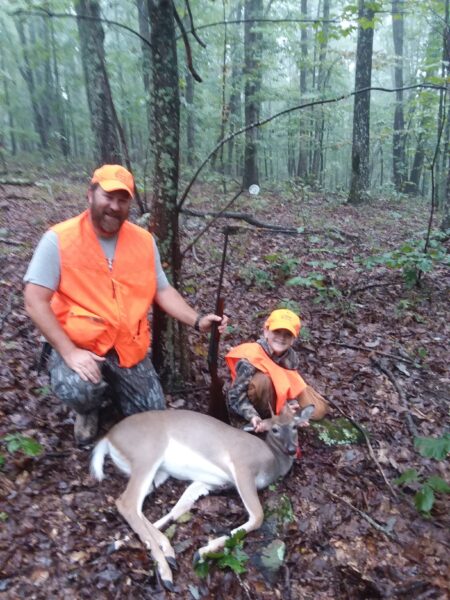 An image of a man and a boy and the deer that they killed