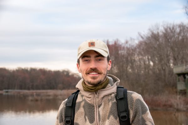 An image of Wade Monroe smiling for a photograph in front of a lake