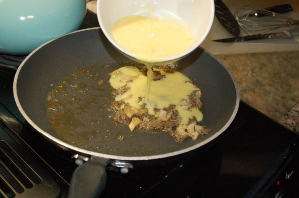 An image of eggs being added to morel mushrooms as they taste very good together.