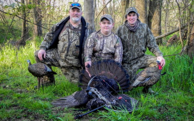 An image of three people and the turkeys they have killed