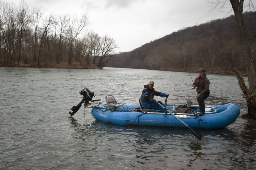 An image of two men in a blue raft fishing on the New River