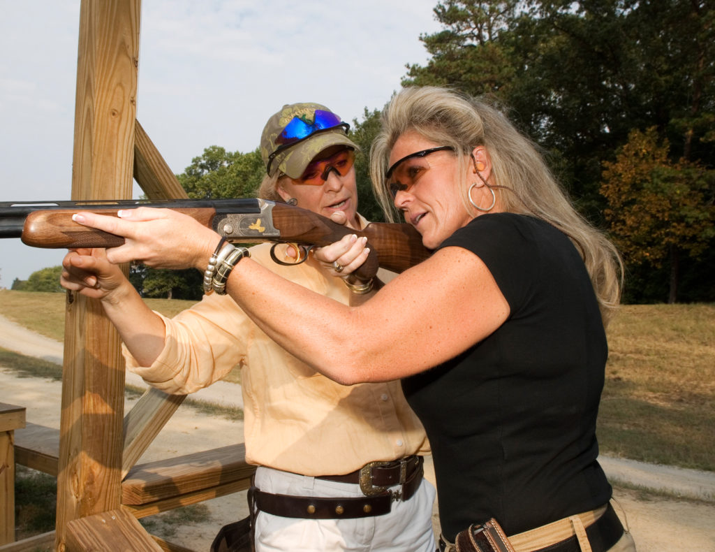 An image of a woman holding a rifle as if to shoot it
